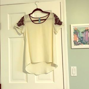 White top with navy embroidery on the sleeves